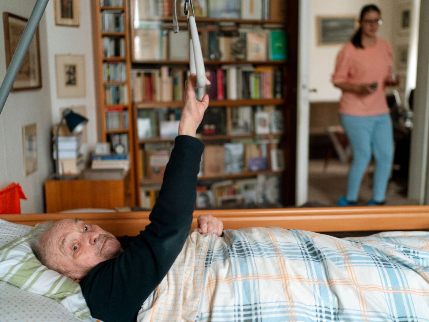 Pflegekraft kümmert sich im Schlafzimmer eines Patienten um dessen Wohlbefinden