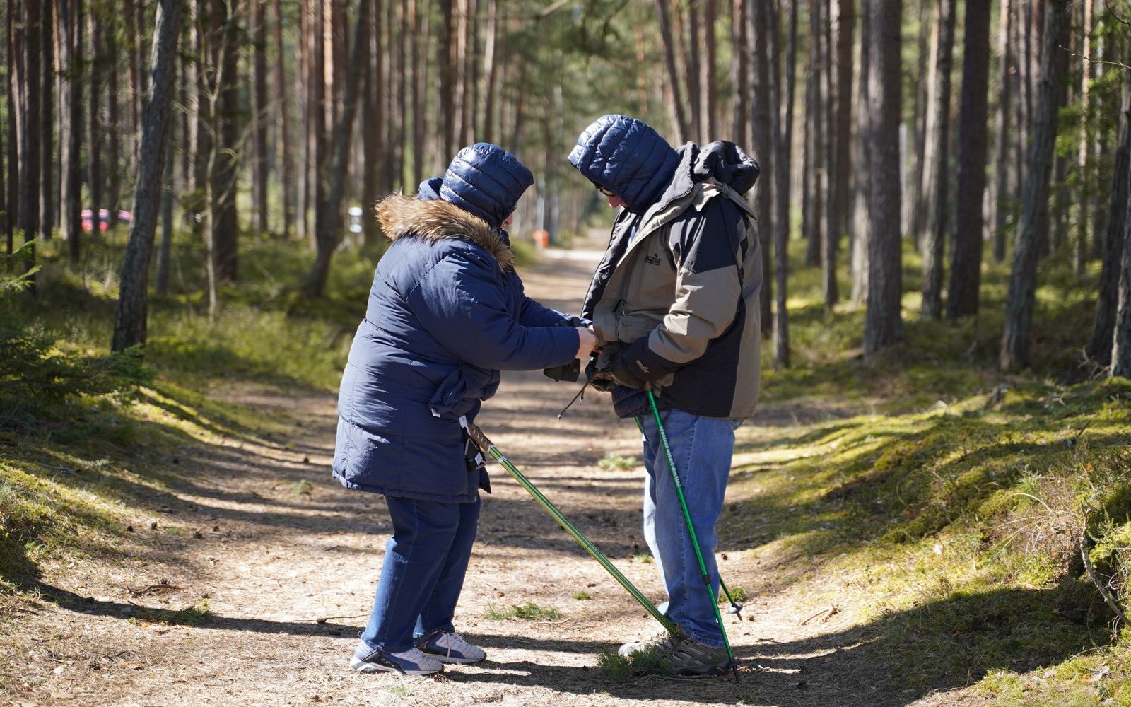 Pflegekraft begleitet einen Senior beim Spaziergang im Wald