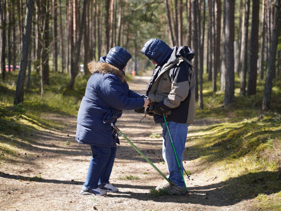 Pflegekraft begleitet einen Senior beim Spaziergang im Wald