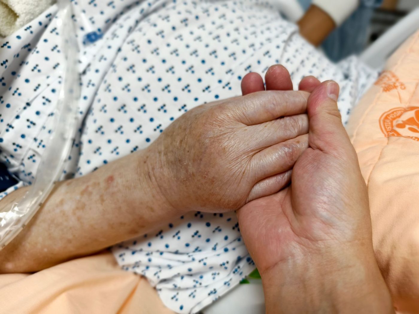Hände einer Pflegekraft bei der Grundpflege im Krankenhausbett