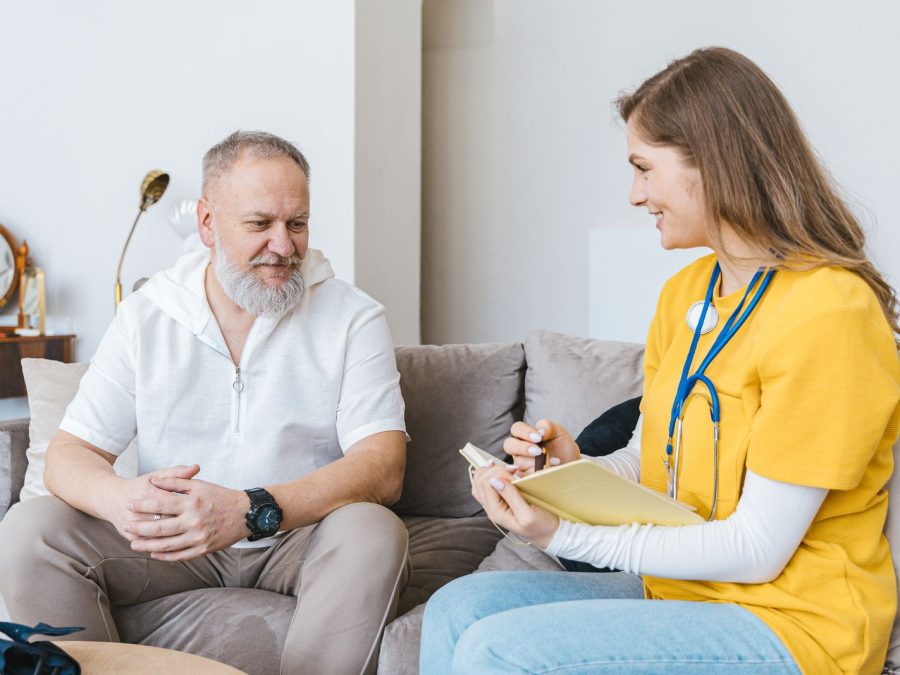 Pflegeberaterin im vertrauensvollen Gespräch mit einer Angehörigen im Wohnzimmer